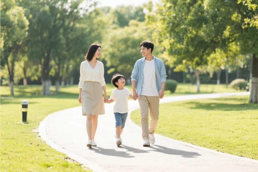 一家三口在公园散步，父母与孩子开心交流，展现健康积极的生活态度